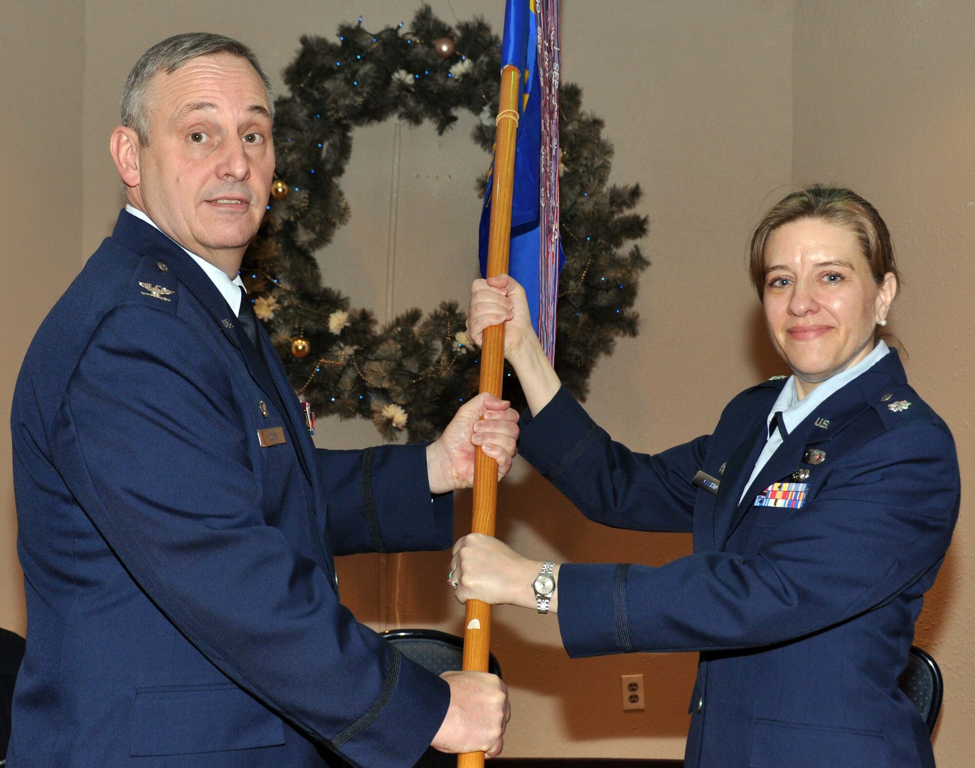 Col. Michael Ochs, 934th Mission Support Group commander, passes the new 934th Force Support Squadron flag to Lt. Col. Erika Cashin as she accepts command of the FSS at a ceremony Dec. 4. (Air Force Photo/Senior Airman Noah Johnson) 