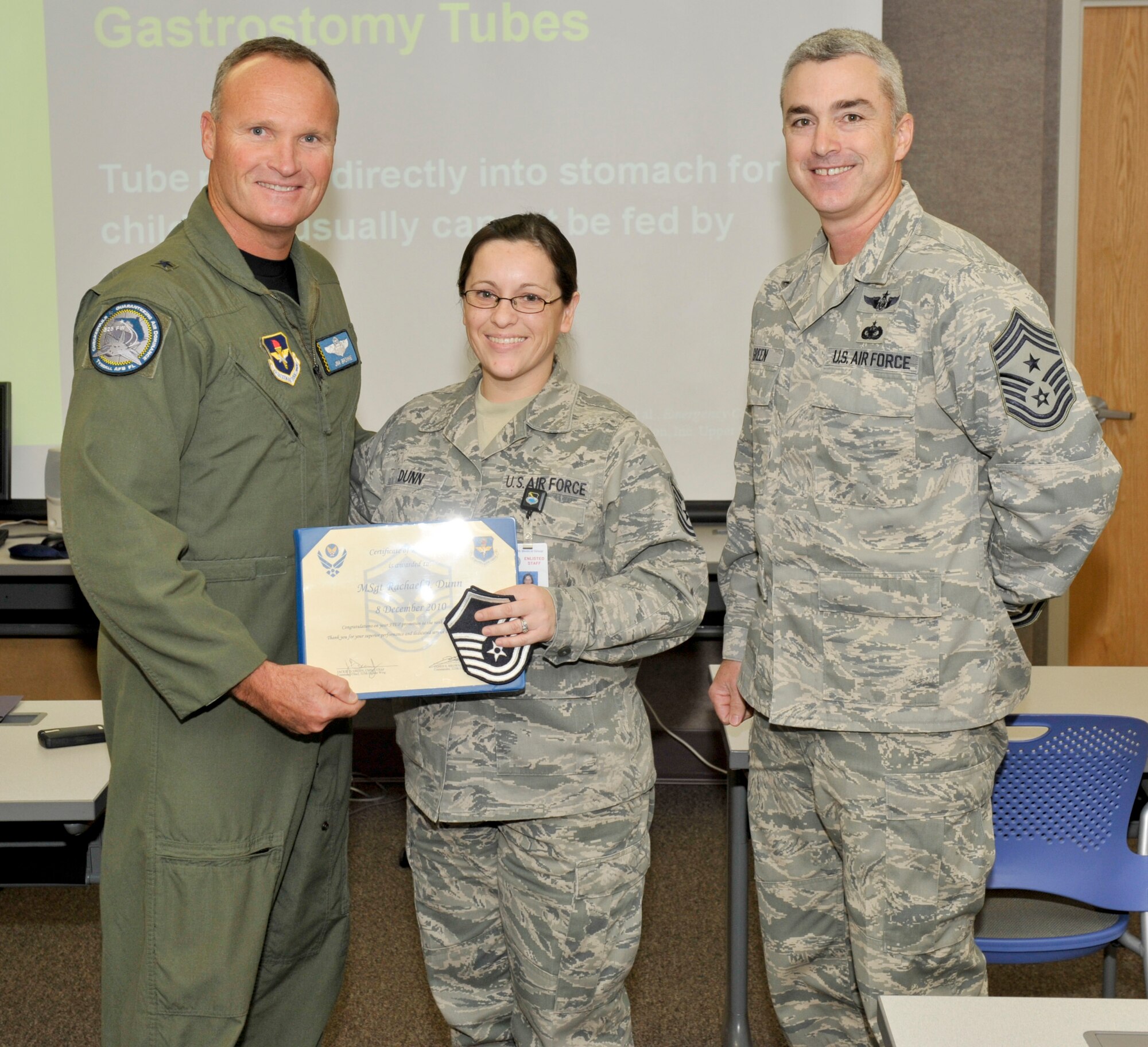 Brigadier General James Browne, 325th Fighter Wing commander, awards Tech. Sergeant Rachael Dunn, 325th Aerospace Medicine Squadron non-commissioned officer in charge of physical standards, with an immediate STEP promotion to Master Sergeant Dec 8. as Chief Master Sgt. Jackie Greene, 325th FW command chief looks on. (U.S. Air Force photo by Jonathan Gibson)