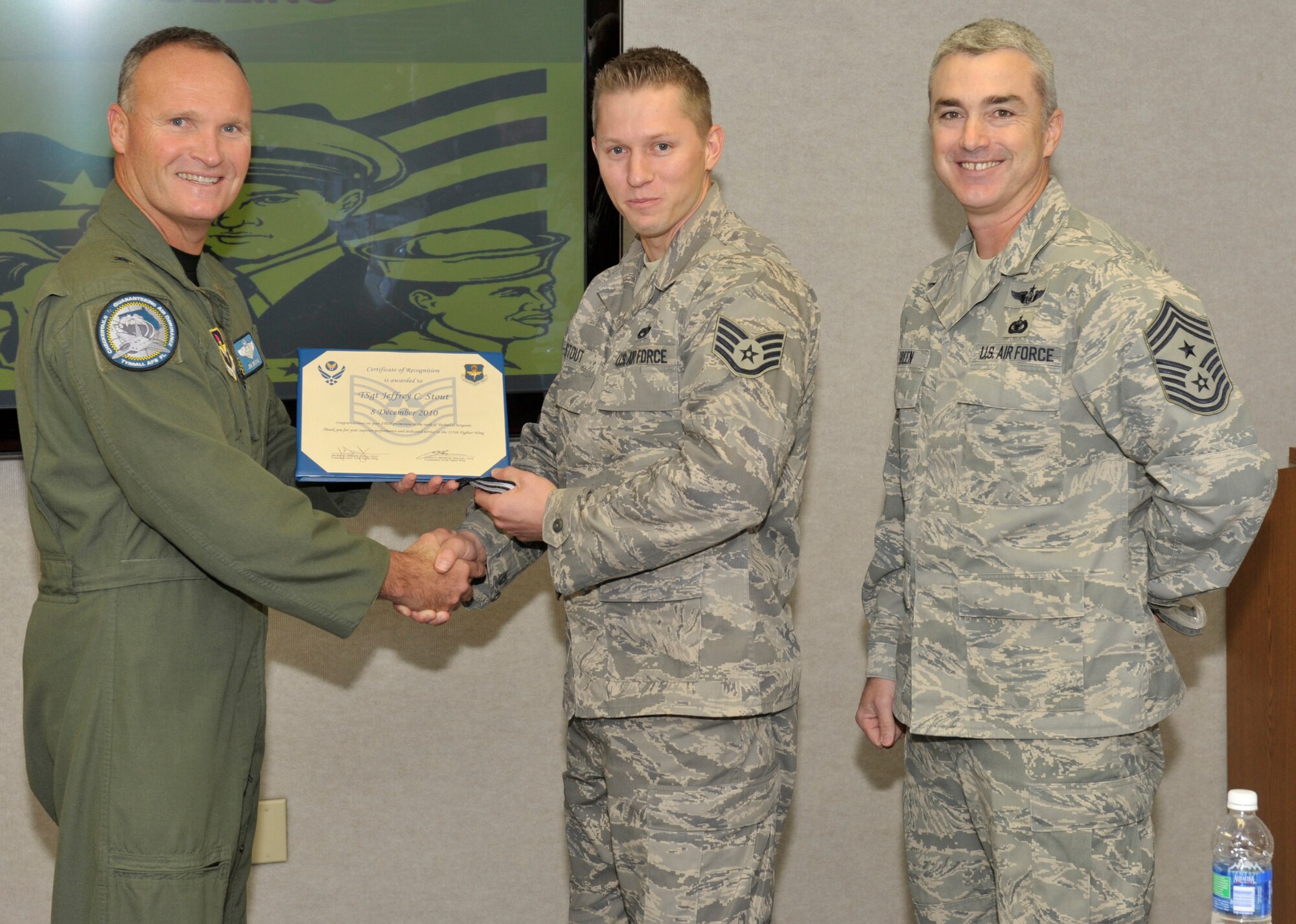 Brigadier General James Browne, 325th Fighter Wing commander, awards Staff Sergeant Jeffrey Stout, 325th Maintenance Operations Squadron quality assurance technician, with an immediate STEP promotion to Technical Sergeant Dec 8. as Chief Master Sgt. Jackie Greene, 325th FW command chief looks on. (U.S. Air Force photo by Jonathan Gibson)