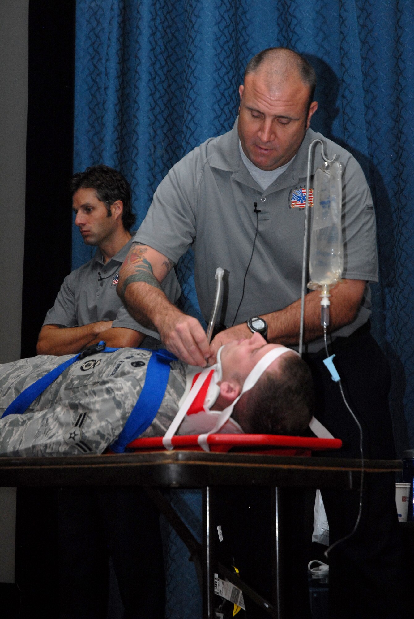 Patrick Kelly, a fire rescue paramedic, demonstrates a tracheotomy on Airman 1st Class Calvin Bostick, 341st Security Forces Group Tactical Response Force member, while Chris Stocks, a fire rescue paramedic, waits for his next demonstration.  The demonstration showed what could happen to someone involved in an alcohol-related accident.