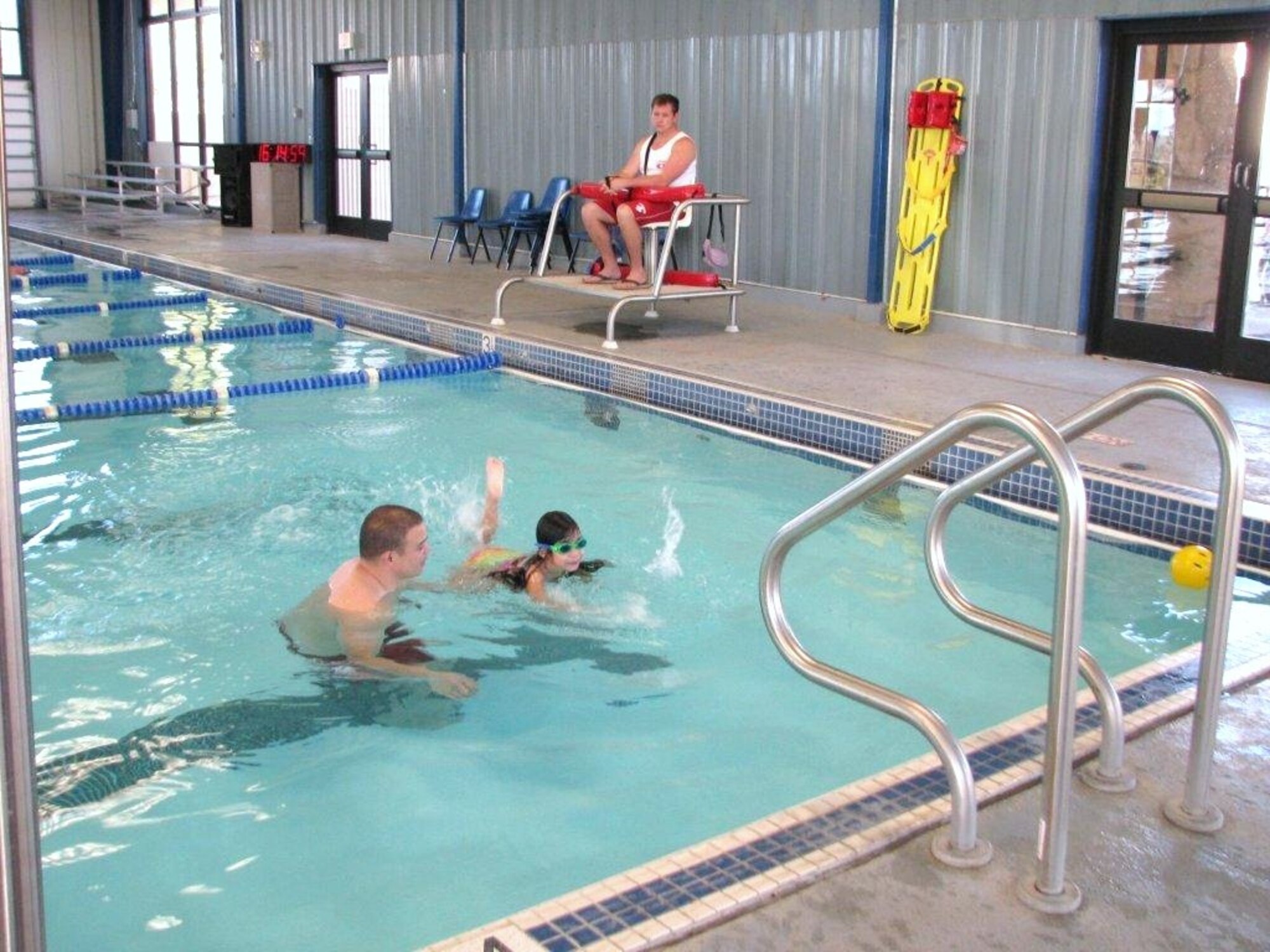 Staff Sgt. Shane Vaughn, 95th Communications Squadron, spends quality time with his 6-year-old daughter Sienna while teaching her to swim at the Oasis Aquatic Center. Lifeguard Donnie Novak observes and is ready for any emergency. (Air Force photo by Diane Betzler)
