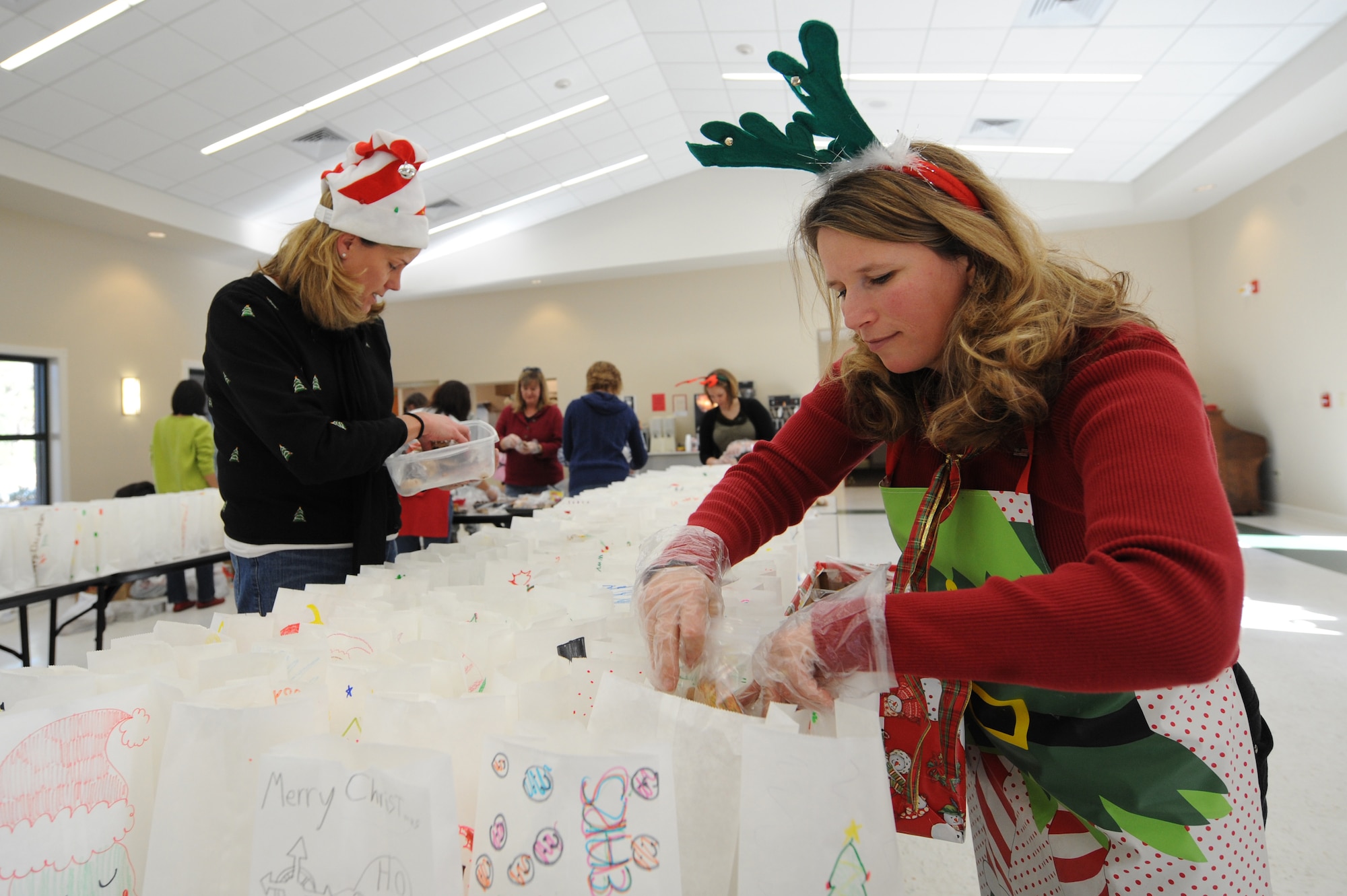 Joan Tufts, right, and Jane Holba place cookies in bags during the annual Team Charleston Spouses' Club Cookie Drop at Joint Base Charleston-Air Base, S.C., Dec. 8, 2010. This year, the TCSC put together more than 500 bags and boxes of holiday cookies for service members living in the base dormitories, eating at the dining facility and who are deployed. Mrs Tufts is wife of Maj. Adam Tufts with the 14th Airlift Squadron, and Mrs. Holba is the wife of Col. Robert Holba who is the 437th Operations Group commander. (U.S. Air Force photo/James M. Bowman)