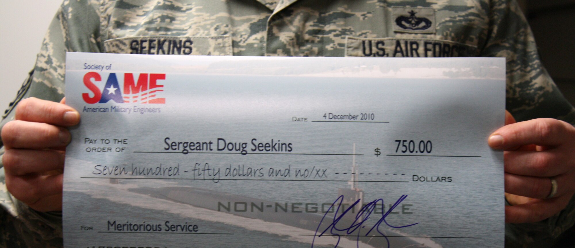 JOINT BASE LEWIS-MCCHORD, Wash.- Tech. Sgt. Doug Seekins, 446th Civil Engineer Squadron water treatment technician, displays his $750 check he received from the Society of American Military Engineers, Dec. 4. Sergeant Seekins and Senior Master Sgt. Bruce Pritchett, 446th CES electrics superintendent, both earned checks for their efforts during their deployment to kirkuk Air Base, Iraq last year. The sergeants plan on using the money for continuing education in their civil engineer trades. (Courtesy photo)