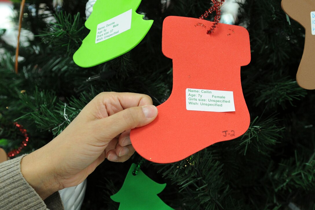LANGLEY AIR FORCE BASE, Va. – Ivelisse Solazayas, Army and Air Force Exchange Service operations manager, selects an underprivileged child’s wish list ornament off the Langley Angel Tree, displayed in the Base Exchange Lobby, Dec. 6. The tree is a part of an annual program that allows individuals to choose an ornament with an underprivileged child’s wish list of gifts so they can buy and wrap gifts for the child during the holidays. (U.S. Air Force photo/Airman 1st Class Racheal Watson)(RELEASED) 