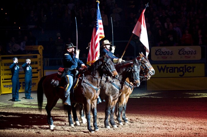 LAS VEGAS -- Members from B Troop, 4th U.S. Cavalry (Memorial), Fort Huachuca, Ariz., and the U.S. Air Force Air Demonstration Squadron "Thunderbirds",  Nellis Air Force Base, Nev., render a salute during the singing of the national anthem at opening ceremony of the National Finals Rodeo at the Thomas and Mack Center Dec. 5. The NFR paid tribute to the men and women of the armed forces for their service to our country. (U.S. Air Force photo by Lawrence Crespo/Released) 