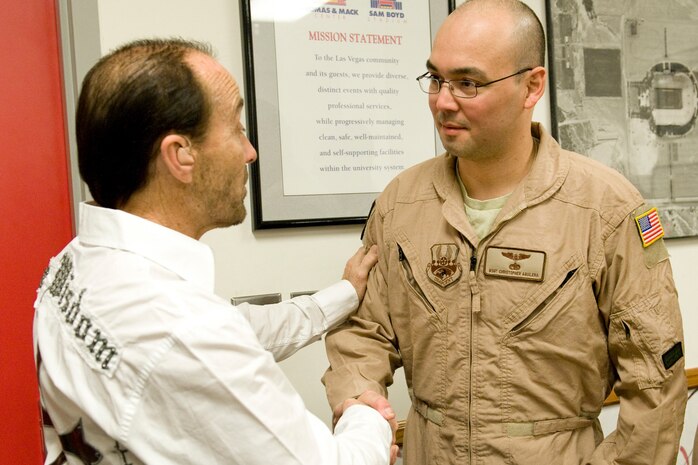 LAS VEGAS --  Country music star Lee Greenwood thanks Master Sgt. Christopher Aguilera, an aerial gunner assigned to the 66th Rescue Squadron, Nellis Air Force Base, Nev., for his honorable service prior to the National Finals Rodeo opening ceremony Dec 5. Sergeant Aguilera recently returned to duty after four months in the hospital from injuries he sustained during his last tour in Afghanistan.  (U.S. Air Force photo by Lawrence Crespo/Released) 