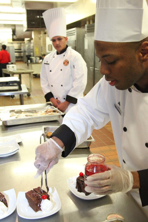 Lance Cpl. Rashaad S. Riboul, front, places a cherry on top of his devil’s food cake for Cherry Point’s first chef of the quarter competition of the fiscal year at the Cherry Point Mess Hall Dec. 9. Lance Cpl. Jose A. Santiago, background, was the victor in the competition. Both Marines are food service specialists with Marine Wing Support Squadron 274.