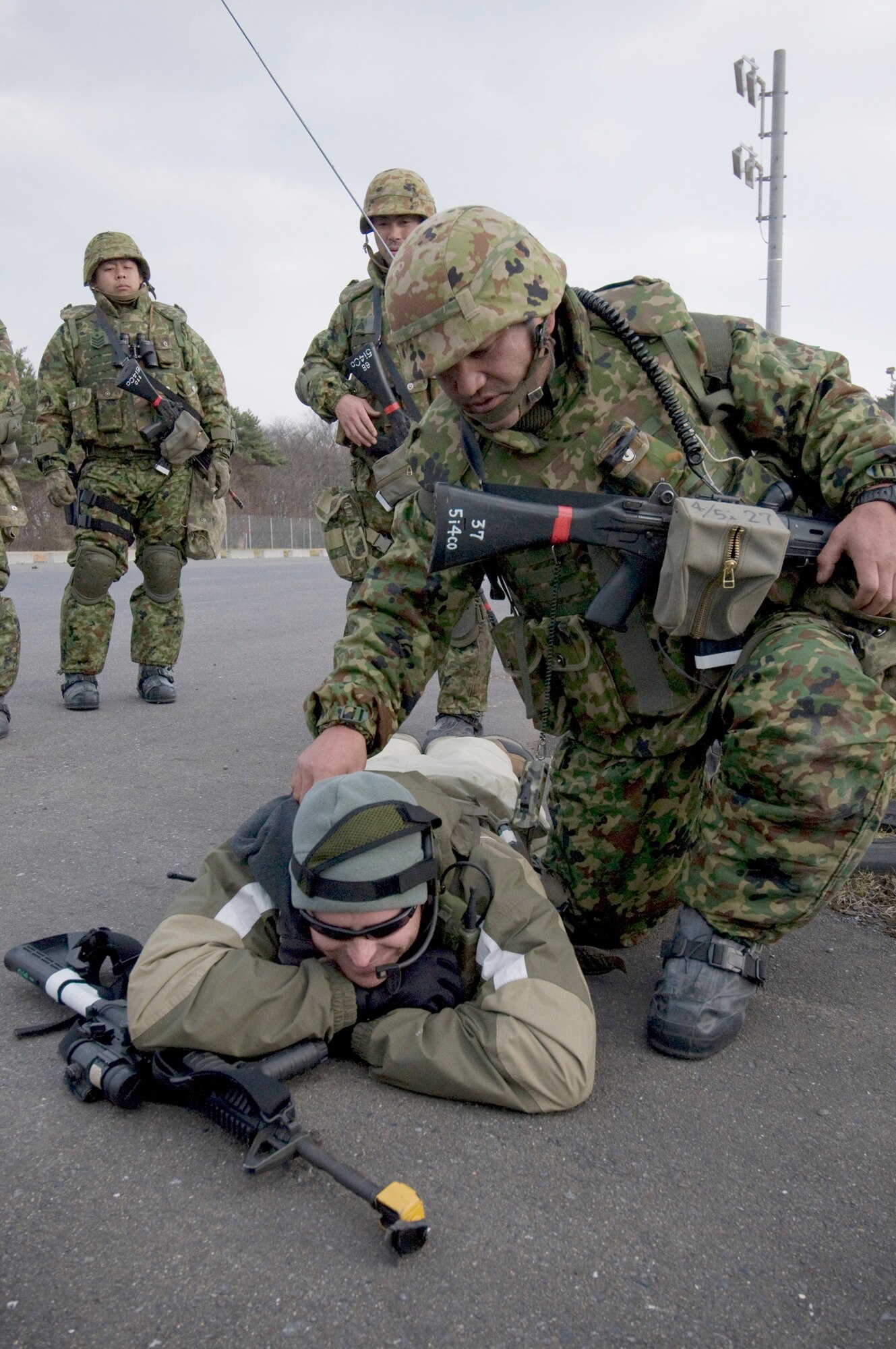 A soldier from Japan Ground Self-Defense Force, 9th Division, 5th Infantry Regiment, Aomori, verifies a simulated kill on Tech. Sgt. Paul Barentine during a bilateral exercise Dec. 5, 2010, at Misawa Air Base, Japan. The JGSDF troops were part of a two-day Guard and Protect Exercise that partnered them with the Japan Air Self-Defense Force 3rd Air Wing and the 35th Security Forces Squadron. Sergeant Barrantine is a 35th Security Forces Squadron member and opposing forces volunteer. (U.S. Air Force photo/Senior Airman Jessica Lockoski)

