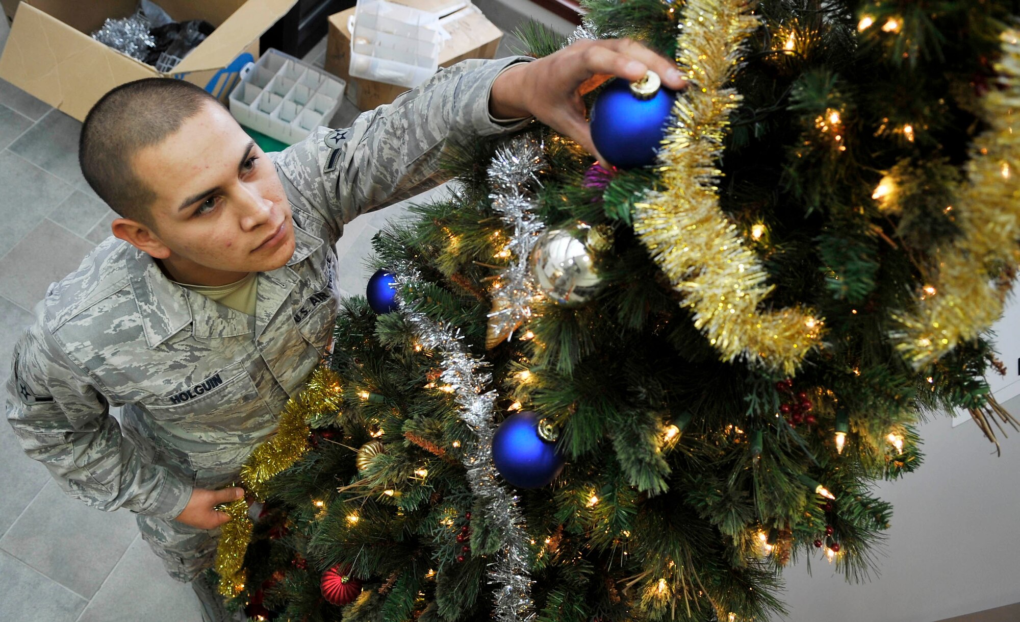 Airman Marc Holguin, 460th Space Communications Squadron puts ornaments on a Christmas decorated tree. Many of buckley's units are beginning to join in on the Christmas celebration.(U.S. Air Force photo by Airman 1st Class Paul Labbe.)