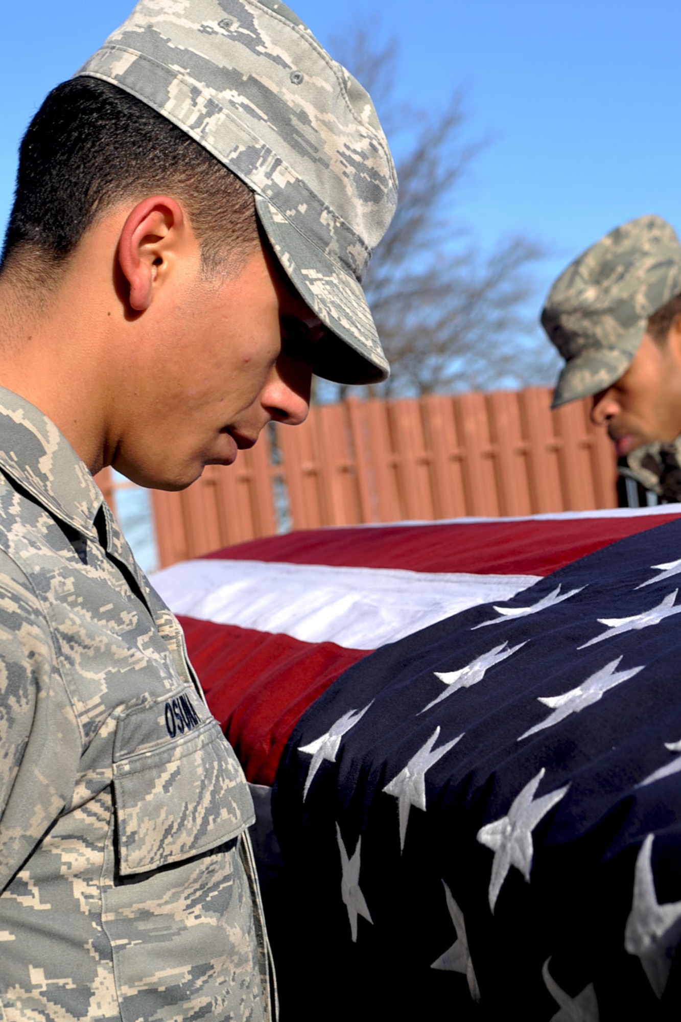LANGLEY AIR FORCE BASE, Va -- Airman 1st Class Jose Osuna, (left),mental health technician with 633d Medical Group, and Senior Airman Gregory Montgomery with 27th Intelligence Squadron, bow their heads before raising the ceremonial casket during honor guard practice, outside the honor guard building Dec. 7. Airmen of the base honor guard volunteer for three months outside of their career fields to perform ceremonial duties for veterans, retirees and active duty members.(U.S. Air Force photo/Staff Sgt. Ashley Hawkins)(RELEASED)