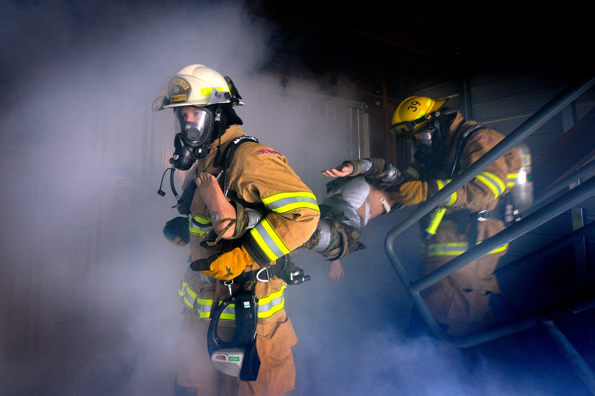 Col. Wayne Monteith, commander of the 50th Space Wing, and firefighter Cody Marion join together to rescue a 'victim' from a smoke-filled room Dec. 3, 2010, in the fire suppression training facility at Schriever Air Force Base, Colo. The commander participated in the training to get firsthand experience.  (U.S. Air Force photo/Dennis Rogers)
