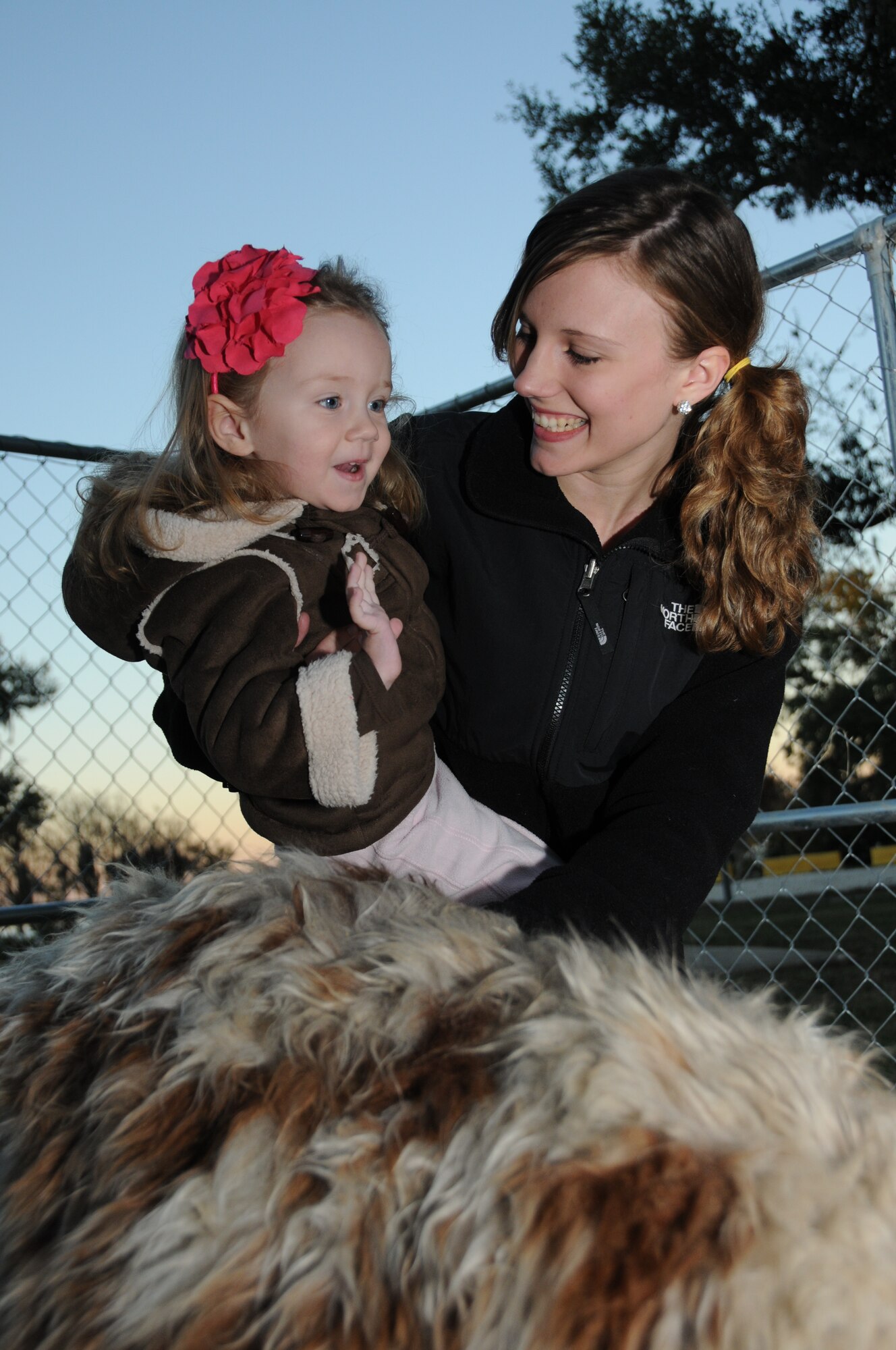 Two-year-old Nevaeh Livingston and her mom Raygen Livingston pet Kuscko, a miniature llama provided by K&B Exotics in St. Martin at Holiday in the Park, Dec. 1 at marina park.  Nevaeh's dad is Airman 1st Class Thomas Livingston, a student in the 338th Training Squadron.  (U.S. Air Force photo by Kemberly Groue)