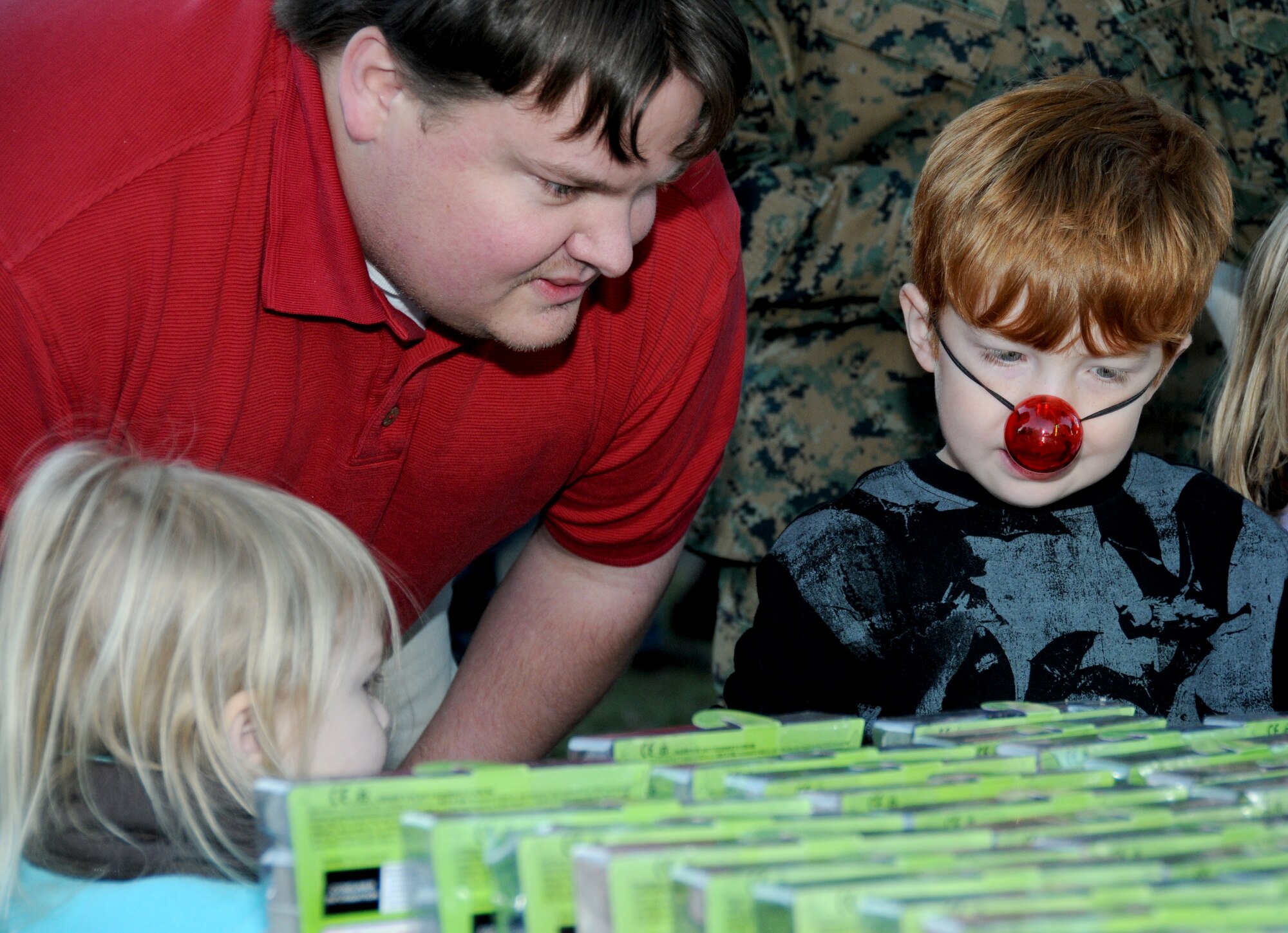From left, Kylie, Paul and Nathan Williams look at items on the free toy table at Holiday in the Park, Dec. 1 at marina park.  Paul is married to 1st Lt. Jennifer Williams, 81st Inpatient Operations Squadron.  Kyle is 3 and Nathan is 6 years old.  (U.S. Air Force photo by Kemberly Groue)