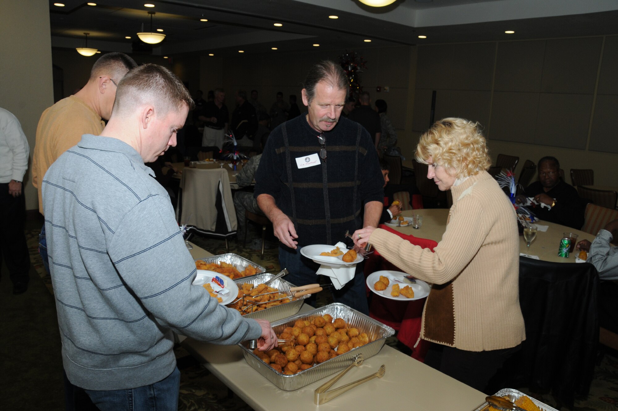 From left, Maj. Jason Kane, Willem Montfoort and his wife, Col. Kim Montfoort fill their plates at the fish fry hosted by the Biloxi Bay Chamber of Commerce.  Major Kane is a member of the Air Force’s A-6 (communications) staff at the Pentagon. Colonel Montfoort is a member of the A-6 staff at Air Force Reserve Command headquarters, Robins Air Force Base, Ga.  (U.S. Air Force photo by Kemberly Groue)