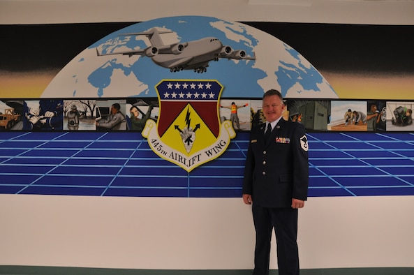 WRIGHT-PATTERSON AIR FORCE BASE, Ohio - Master Sgt. Roland Stinnette, 445th Maintenance Operations Flight, stands by his latest mural located in building 4012, 445th Maintenance Group.  The mural took more than three weeks to complete and represents the 445th Airlift Wing and all the different units working together as a cohesive unit. (U.S. Air Force Photo/Staff Sgt. Amanda Duncan)