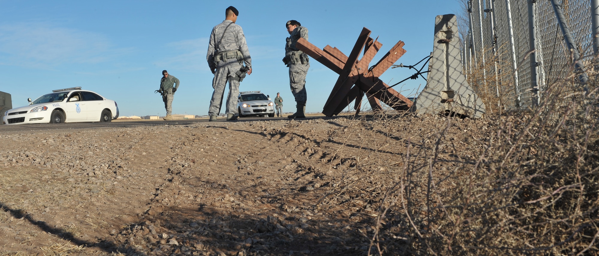 Members of the 27th Special Operations Security Forces Squadron block a section of Perimeter Road at Cannon Air Force Base, N.M., Dec. 8, in preparation for the arrival of a C-130 fuselage trainer. Because of the size of the trainer, a larger entrance  expedited getting the trainer into the base.  (U.S. Air Force photo by Senior Airman James Bell)