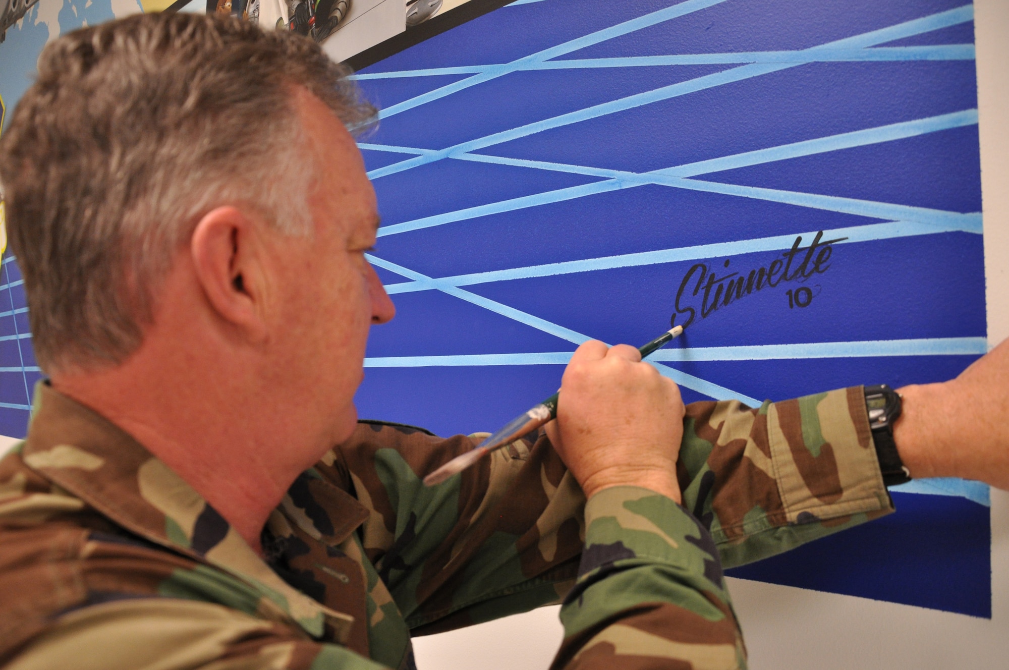 WRIGHT-PATTERSON AIR FORCE BASE, Ohio - Master Sgt. Roland Stinnette, 445th Maintenance Operations Flight, puts the finishing touches on his mural located in building 4012, 445th Maintenance Group.  The mural took more than three weeks to complete and represents the 445th Airlift Wing and all the different units working together as a cohesive unit. (U.S. Air Force Photo/Staff Sgt. Amanda Duncan)