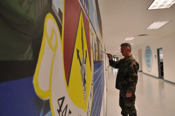 WRIGHT-PATTERSON AIR FORCE BASE, Ohio - Master Sgt. Roland Stinnette, 445th Maintenance Operations Flight, puts the finishing touches on his mural located in building 4012, 445th Maintenance Group.  The mural took more than three weeks to complete and represents the 445th Airlift Wing and all the different units working together as a cohesive unit. (U.S. Air Force Photo/Staff Sgt. Amanda Duncan)