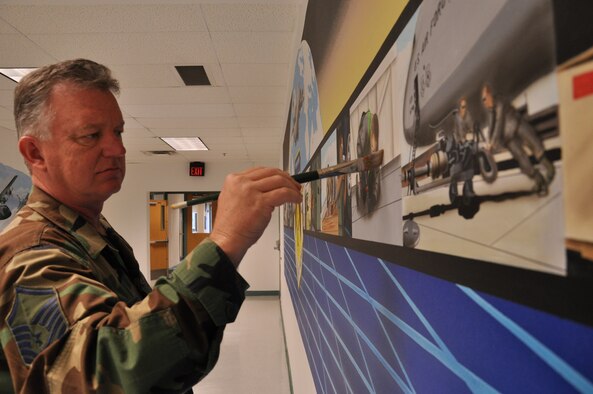 WRIGHT-PATTERSON AIR FORCE BASE, Ohio - Master Sgt. Roland Stinnette, 445th Maintenance Operations Flight, puts the finishing touches on his mural located in building 4012, 445th Maintenance Group.  The mural took more than three weeks to complete and represents the 445th Airlift Wing and all the different units working together as a cohesive unit. (U.S. Air Force Photo/Staff Sgt. Amanda Duncan)