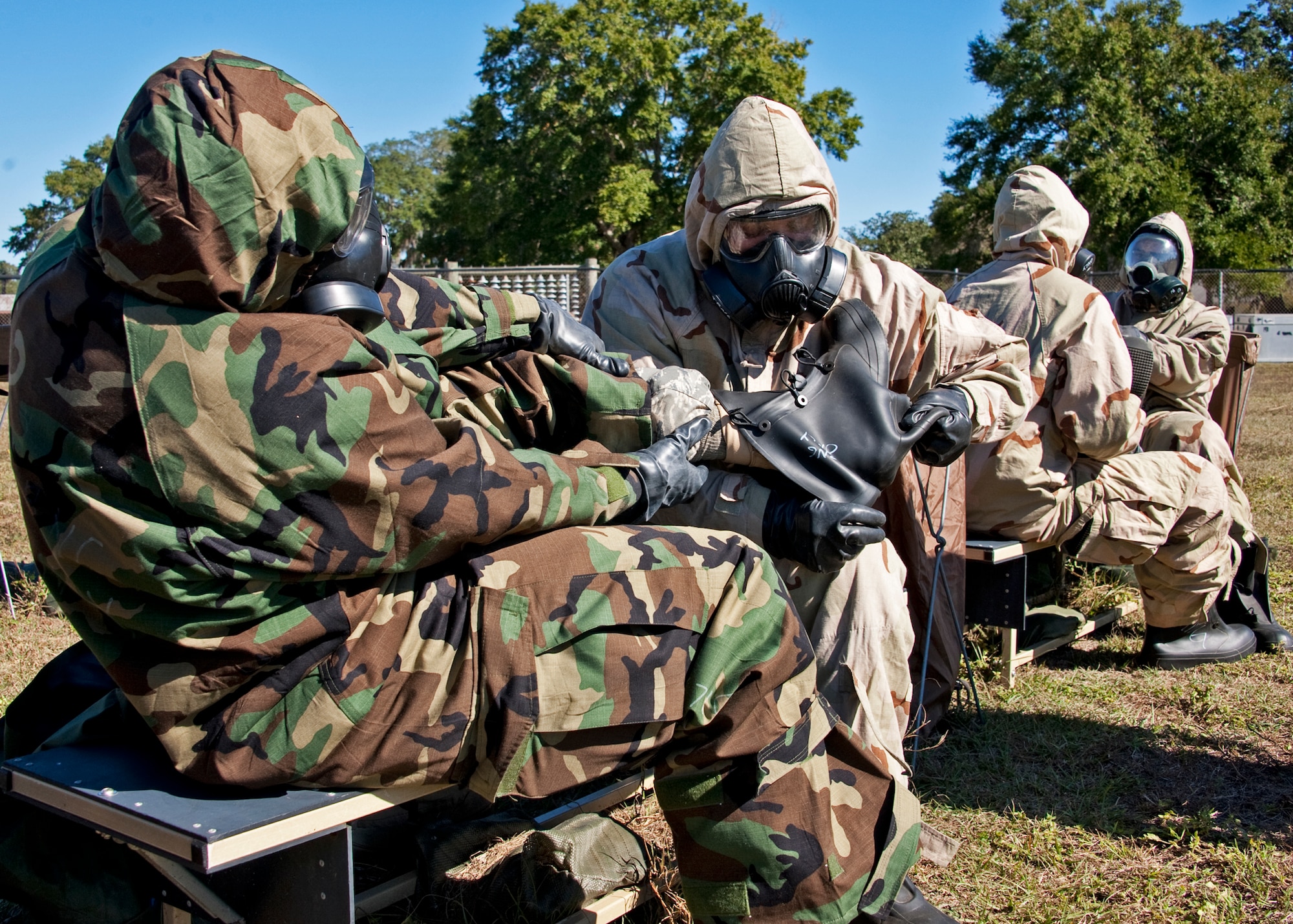 Pairs of Airmen remove the rubber overboots as they progress through the decontamination area at the chemical, biological, radiological, nuclear and explosive training course at Eglin Air Force Base, Fla.  The eight-hour course combines computer based and hands-on training on how and when to wear the gear, UXOs and protective measures.  The 96th Civil Engineer Squadron’s emergency readiness flight teaches the hands-on course up to 75 times a year.  (U.S. Air Force photo/ Samuel King Jr.)