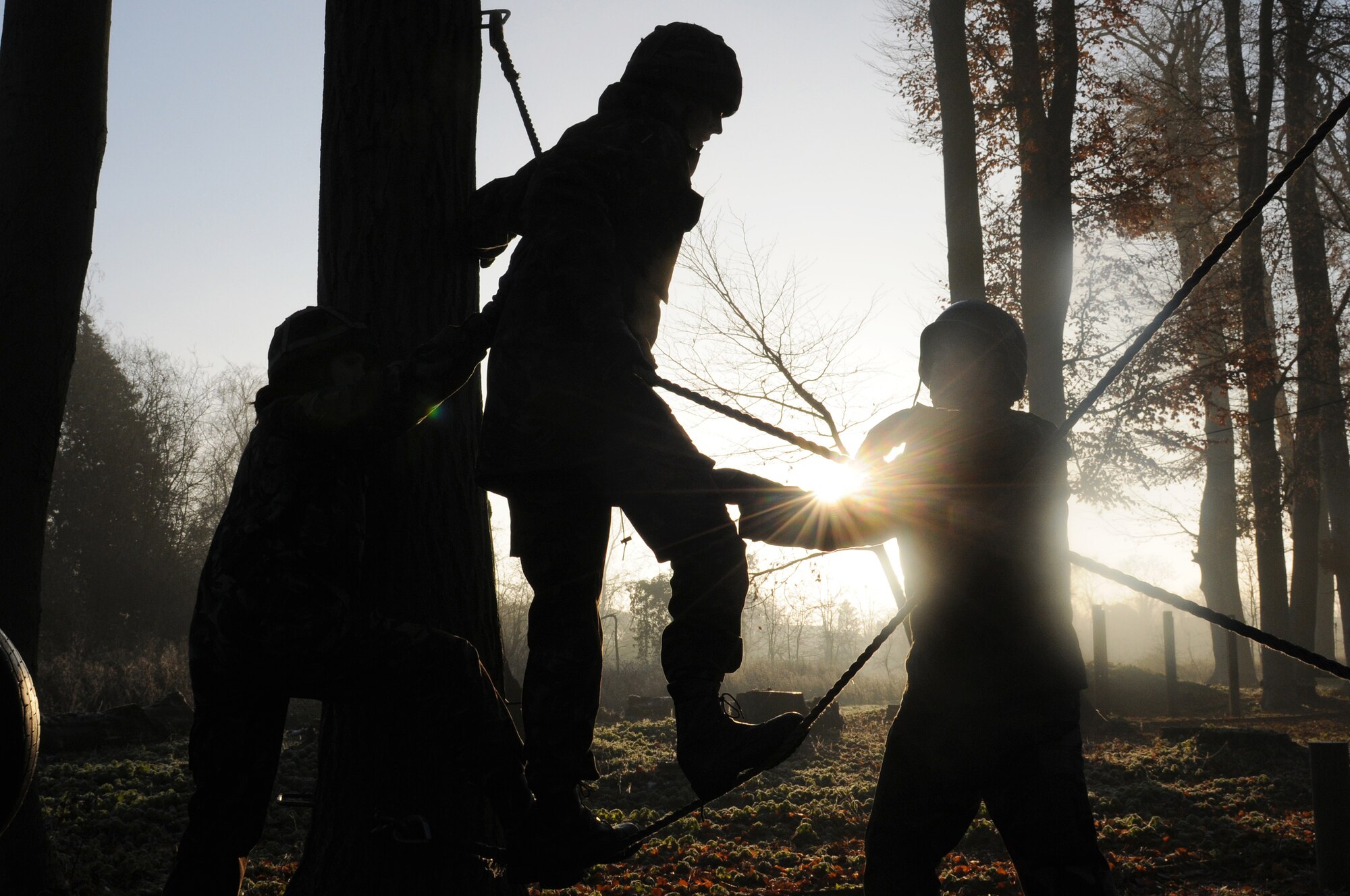 RAF MARHAM, England -- Airmen from RAFs Mildenhall and Marham help a teammate cross a set of ropes at the low-ropes course during Leader, Ethos and Air Power Training Day here Dec. 6, 2010. This activity required leadership and mental and physical strength of participants to get all team members to the finishing point. (U.S. Air Force photo/Senior Airman Tabitha M. Lee)