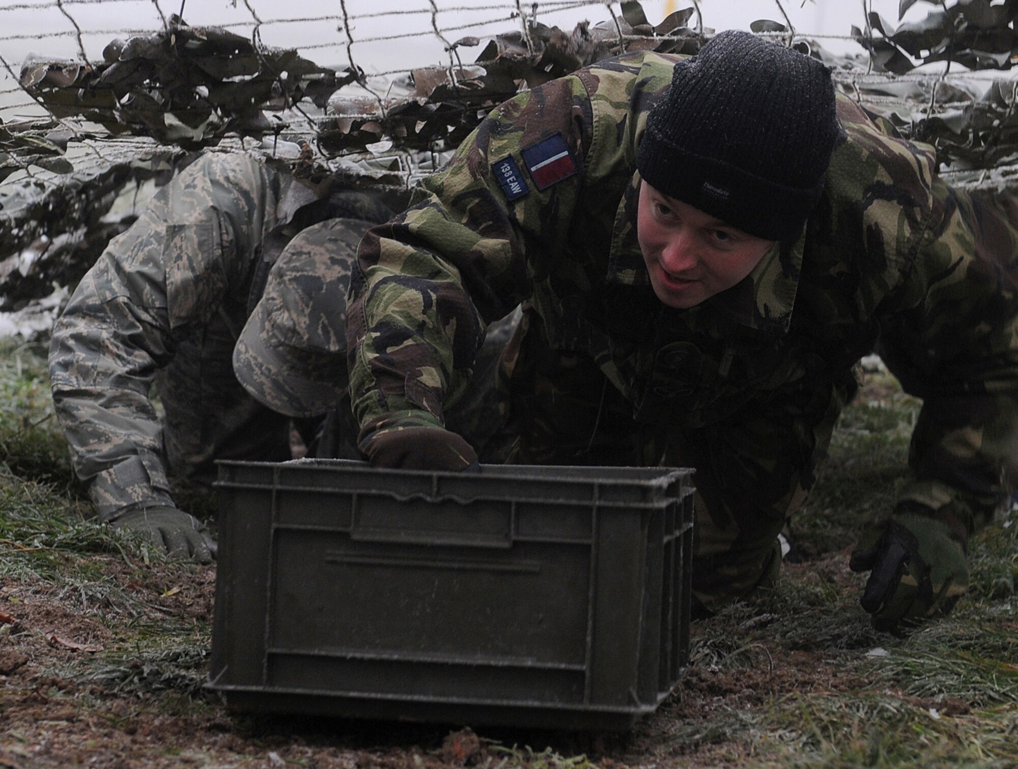 RAF MARHAM, England -- Royal Air Force Senior Aircraftman Technician Martin Dovey, 31st Squadron, RAF Marham, brings a plastic box through a net tunnel as part of a team building exercise during Leader, Ethos and Air Power Training Day here Dec. 6, 2010. Participants for Station LEAP Day were taken from all sections of RAFs Marham and Mildenhall. (U.S. Air Force photo/Senior Airman Tabitha M. Lee) 
