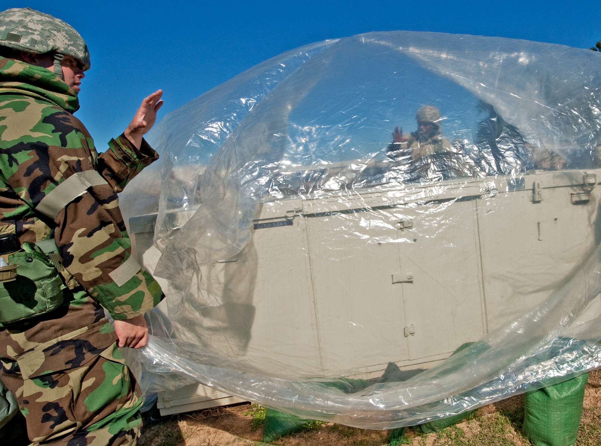 Airmen place a protective covering over vital equipment prior to a simulated attack during the chemical, biological, radiological, nuclear and explosive training course at Eglin Air Force Base, Fla.  The eight-hour course combines computer based and hands-on training on how and when to wear the gear, unxploded ordnances and protective measures.  The 96th Civil Engineer Squadron’s emergency readiness flight teaches the hands-on course up to 75 times a year.  (U.S. Air Force photo/ Samuel King Jr.)