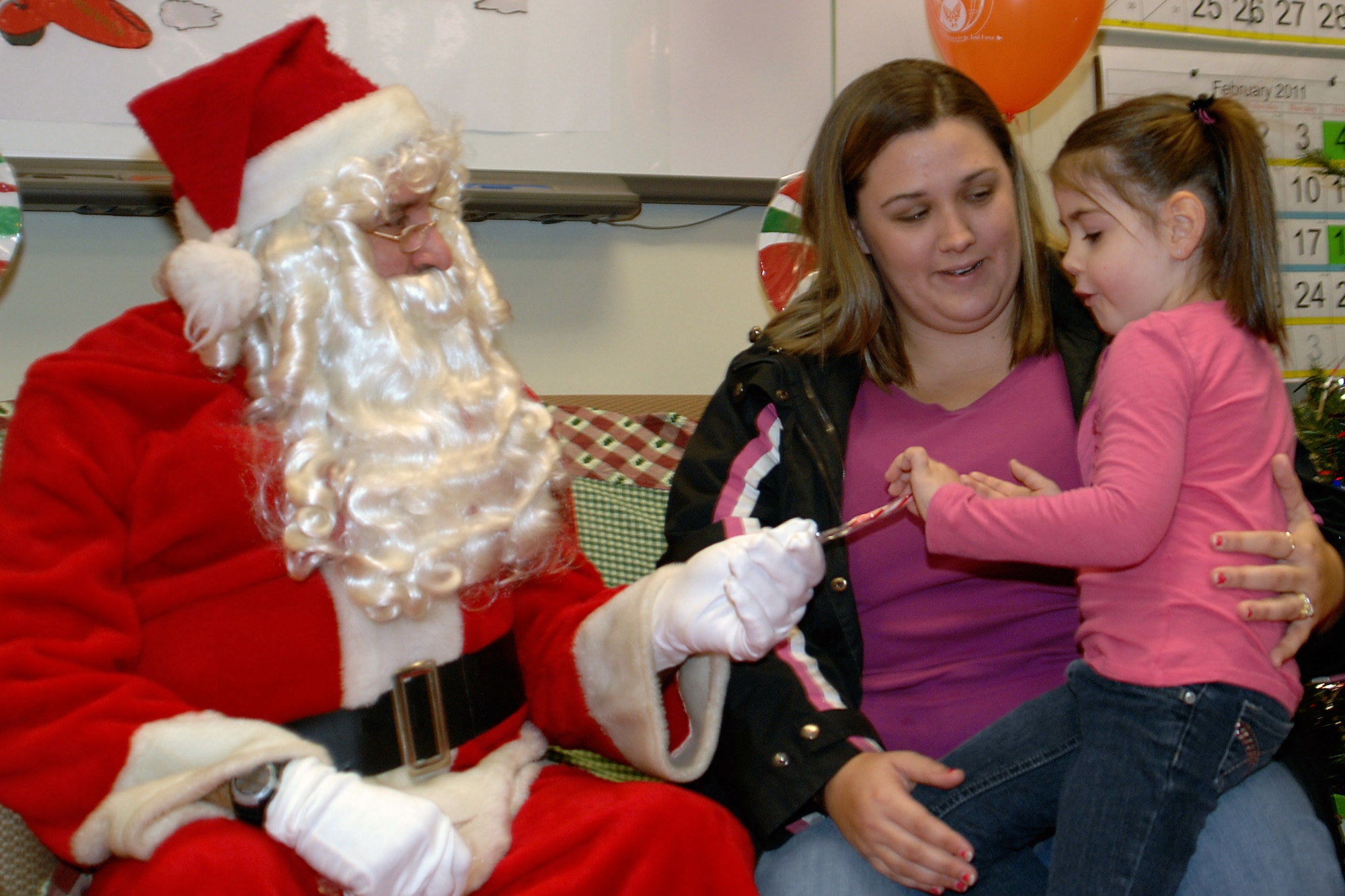 GRISSOM AIR RESERVE BASE, Ind. -- Santa gives Lauren a candy cane as she sits with her mother, Jaci Jackson, during a Grissom Airman and Family office Christmas party. Ms. Jackson is a housekeeping services manager with the Grissom Inn. (U.S. Air Force photo/Senior Airman Andrew McLaughlin)
