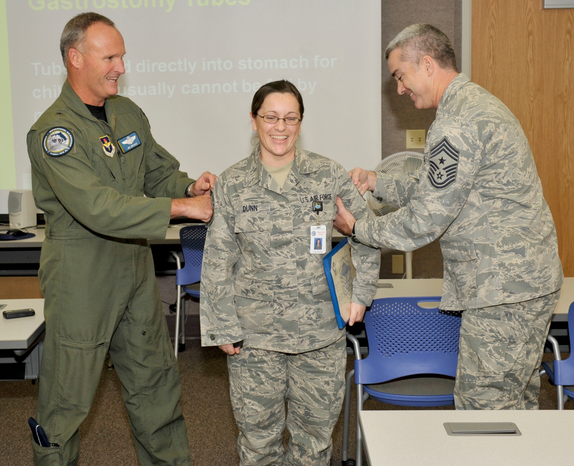 Brigadier General James Browne, 325th Fighter Wing commander, and Chief Master Sgt. Jackie Green, 325th FW command chief, tack on Master Sergeant stripes onto Technical Sergeant Rachael Dunn, 325th Aerospace Medicine Squadron noncommissioned officer in charge of physical standards, as part of the STEP promotion program Dec 8. (U.S. Air Force photo by Jonathan Gibson)  