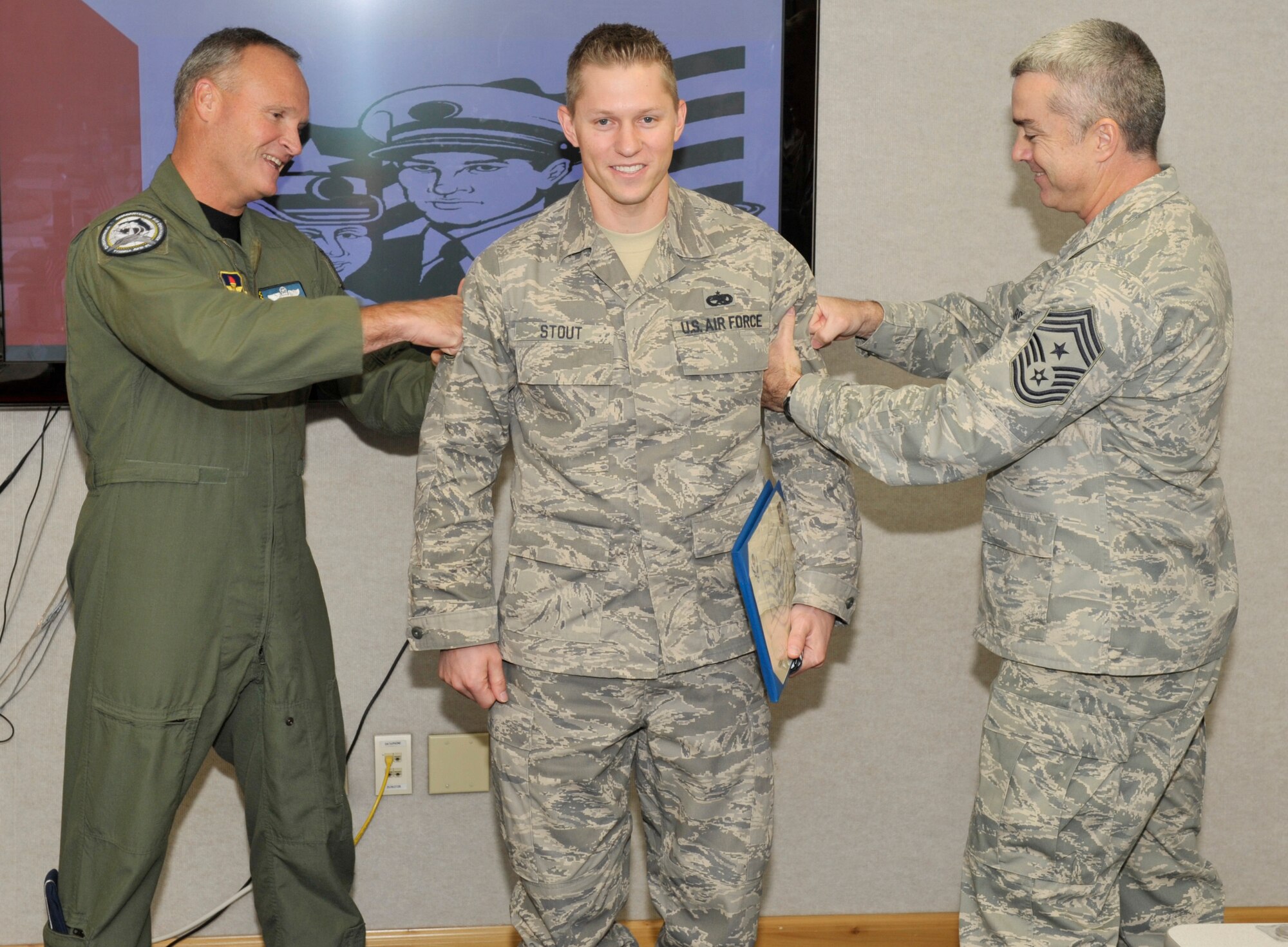 Brigadier General James Browne, 325th Fighter Wing commander, and Chief Master Sgt. Jackie Green, 325th FW command chief, tack on Technical Sergeant stripes onto Staff Sergeant Jeffrey Stout, 325th Maintenance Operations Squadron quality assurance technician, as part of the STEP promotion program Dec 8. (U.S. Air Force photo by Jonathan Gibson)  