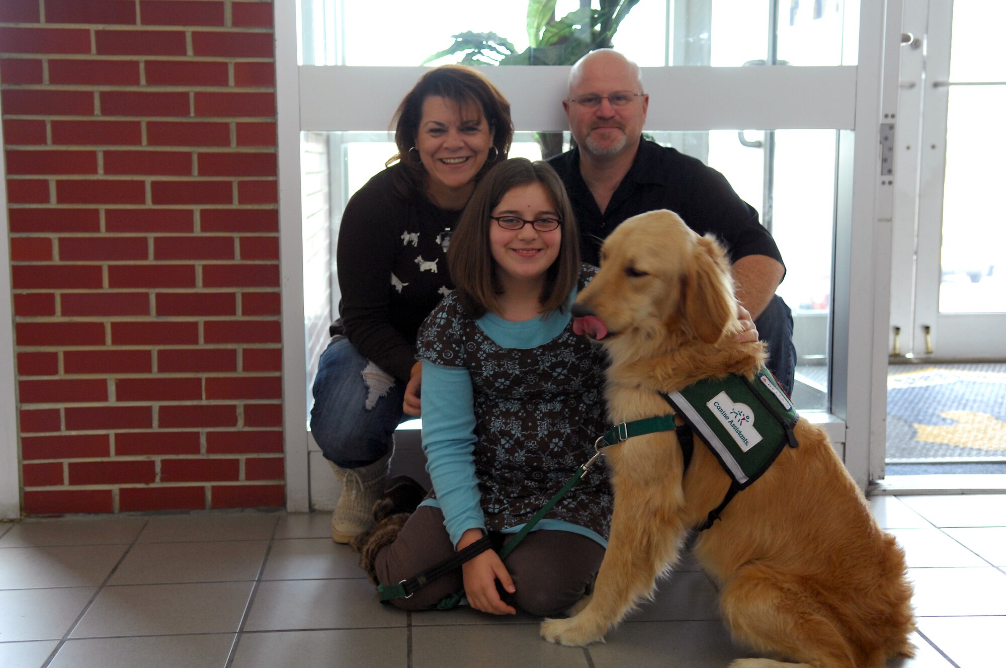 Gabriella, Lisa and Master Sgt. (Ret.) Kenneth Thayer, pose for a photo with Gabby's new canine assistance dog, Flint. In early November, Gabby attended a two-week training course to learn about assistant dogs training and their relationship to humans. (U.S. Air Force photo/Airman 1st Class Kate Wetherby)