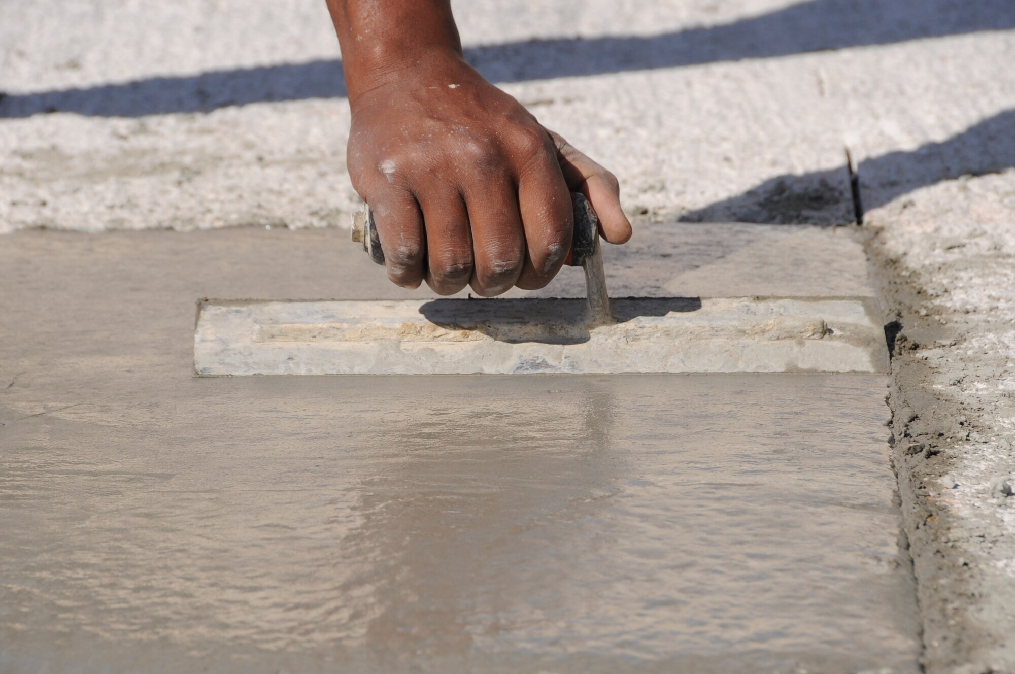 Staff Sgt. Kellen Wilson, 380th Expeditionary Civil Engineer Squadron pavements and construction equipment operator, evens out a slab of newly poured concrete Dec. 6, 2010 at an undisclosed location in Southwest Asia. The new concrete is for an aircraft tie down project that supports multiple types of aircraft. (U.S. Air Force photo/Tech Sgt April Wickes)


