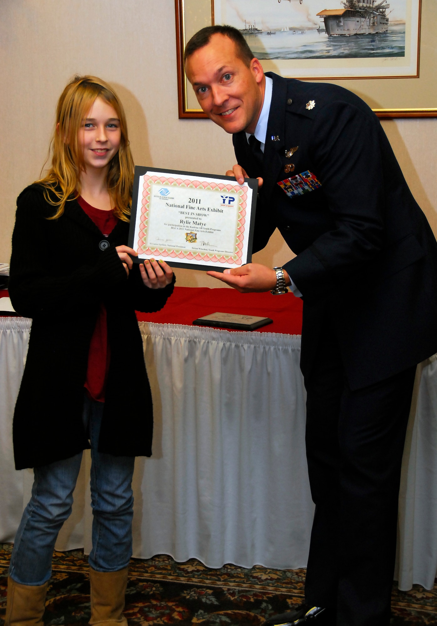 Rylie Matye, 12, receives the "Best in Show" award from Lt. Col. Michael Borgert, 18th Force Support Squadron commander, for her artwork at the Boys and Girls Club of America Fine Arts Exhibit at the Kadena Officers' Club, Dec. 8. Rylie is the daughter of Master Sgt. John Matye, 353rd Special Operations Group, and Tech. Sgt. Angela Matye, 44th Fighter Squadron. (U.S. Air Force photo/ Airman 1st Class Maeson L. Elleman)