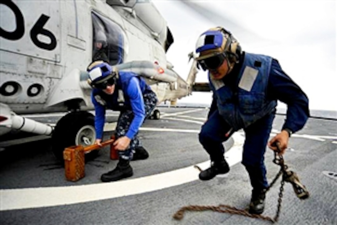 U.S. Navy Petty Officer 3rd Class Jeremy Lingle, left, and Petty Officer 3rd Class Jade Secretaria remove a chock and chains from a Japan Maritime Self-Defense Force SH-60K Seahawk helicopter before takeoff from amphibious dock landing ship USS Tortuga in the Philippine Sea, Dec. 7, 2010, in the Philippine Sea. The Tortuga is part of the USS Essex Expeditionary Strike Group, which participated in exercise Keen Sword with the Japan Maritime Self-Defense Force.