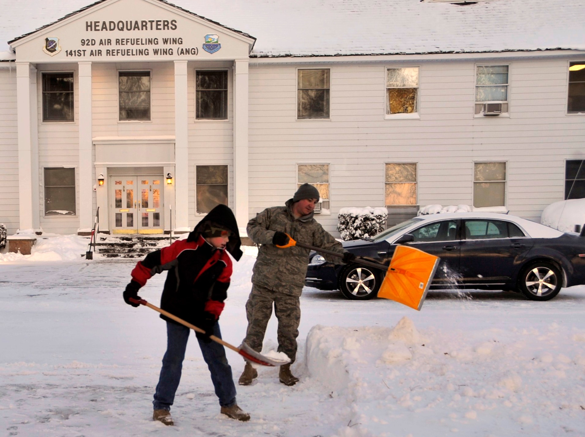 FAIRCHILD AIR FORCE BASE, Wash. -- Staff Sgt. J.G. Buzanowski and his son, Zachary, 9, shovel snow from the front of the wing headquarters building Nov. 24. Sergeant Buzanowski is the NCO-in-charge of the 92nd Air Refueling Wing Public Affairs office. (U.S. Air Force photo/Airman 1st Class Mary Norenberg)