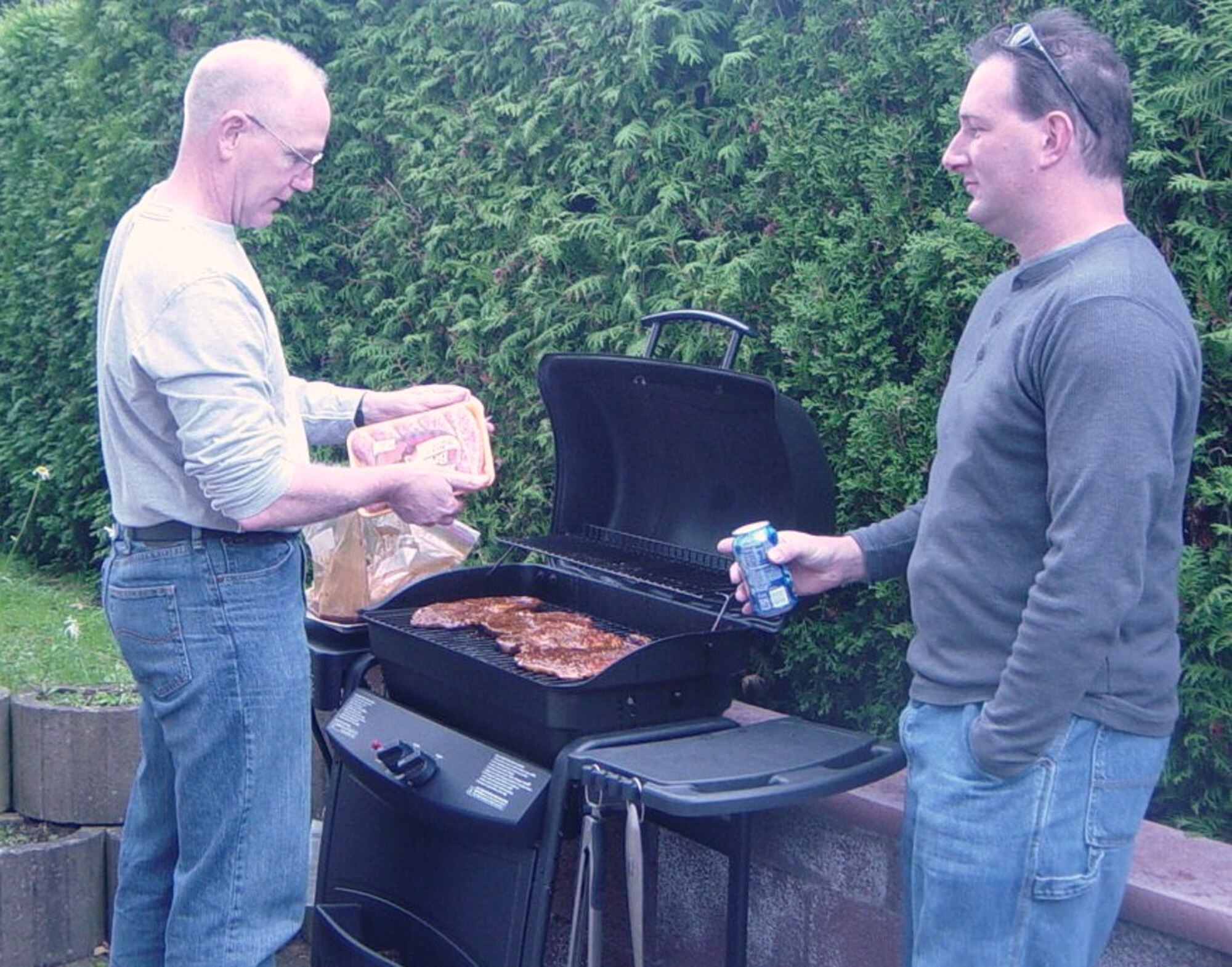 Lt. Col. Dale Pudwill, a Reservist with the 86th Services Squadron, grills dinner in his backyard as an airman from the 940 Wing, visits with his former flight commander.  Pace and eight other Reservists from the 940th SVF at Beale Air Force Base, Calif., served their annual tour with the 86 FSS, Ramstein Air Base, Germany, in October. (U.S. Air Force photo/Tech. Sgt. Glenn Ellin)