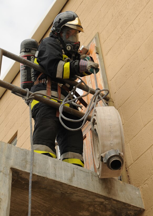 SOTO CANO AIR BASE, Honduras -- A Honduran firefighter pulls a fire hose up one story during the opening obstacle of the "confidence course" during Central America Sharing Mutual Operational Knowledge and Experiences, or CENTAM SMOKE, here Dec. 6. Other stations included a ladder climb and a body carry. (U.S. Air Force photo/Tech. Sgt. Benjamin Rojek)