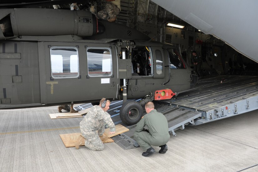 SOTO CANO AIR BASE, Honduras --  Using plywood squares, a member of the 1-228th Aviation Regiment and an aircrew member from McChord AFB, Wash., ensure a Black Hawk helicopter clears the loading ramp as it's taken out of a C-17 Globemaster III here Dec. 9. (U.S. Air Force photo/Tech. Sgt. Benjamin Rojek)