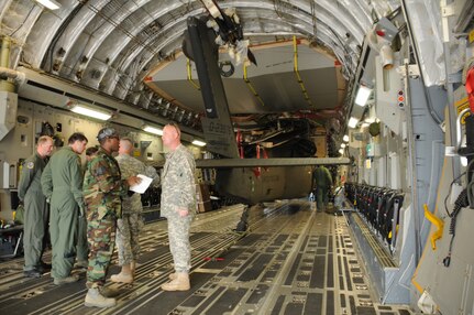 SOTO CANO AIR BASE, Honduras --  With the Black Hawk still locked in place, members of Joint Task Force-Bravo and crewmembers of the C-17 Globemaster III out of McChord AFB, Wash., prepare to unload the helicopter here Dec. 9. The Black Hawk was returned to the 1-228th Aviation Regiment after being sent to the U.S. for repairs. (U.S. Air Force photo/Tech. Sgt. Benjamin Rojek)