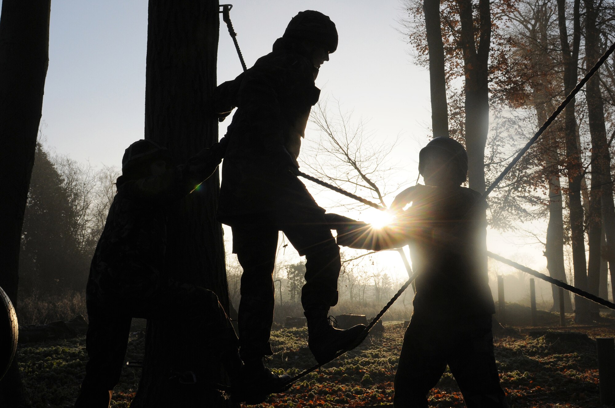 Airmen from Royal Air Force Mildenhall, England, and RAF Marham, England, help a teammate cross a set of ropes at the low-ropes course during Leader, Ethos and Air Power Training Day Dec. 6, 2010, at Royal Air Force Marham, England. This activity required leadership and mental and physical strength of participants to get all team members to the finishing point. (U.S. Air Force photo/Senior Airman Tabitha M. Lee)