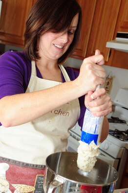 Jessica Kelly, wife of Staff Sgt. Patrick Kelly, 2nd Civil Engineer Squadron, squeezes cookie dough into a mixing bowl at her home on Barksdale Air Force Base, La., Dec. 6. Mrs. Kelly prepared raspberry cookie bars to donate to Barksdale’s annual dorm cookie drive to help boost holiday season morale among dorm residents. (U.S. Air Force photo/Senior Airman Joanna M. Kresge)