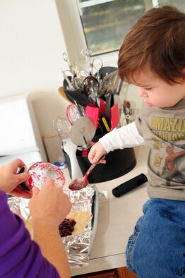 Jody Kelly, 1, son of Staff Sgt. Patrick Kelly, 2nd Civil Engineer Squadron, helps his mom, Jessica, bake cookies for the dorm cookie drive in their home on Barksdale Air Force Base, La., Dec. 6. Cookies were collected, bagged and delivered to dorm residents to raise morale during the holiday season. (U.S. Air Force photo/Senior Airman Joanna M. Kresge)