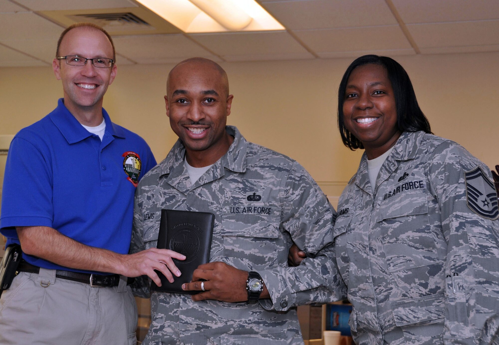 TRAVIS AIR FORCE BASE, Calif. --Master Sgt. Ganell Lewis, center, 349th Memorial Affairs Squadron, was surprised by Mr. Trevor Dean and Senior Master Sgt. Michelle Williams, with Senior Noncommissioned Officer of the Month for October. Mr. Dean is the Deputy Commander, and Sergeant Williams is a director of operations for the Air Force Mortuary Affairs Operations Center, Dover AFB, Del. Sergeant Lewis is deployed there with a team of reservists from the 349th MAS. (U.S. Air Force photo/Staff Sgt. Jamie George)