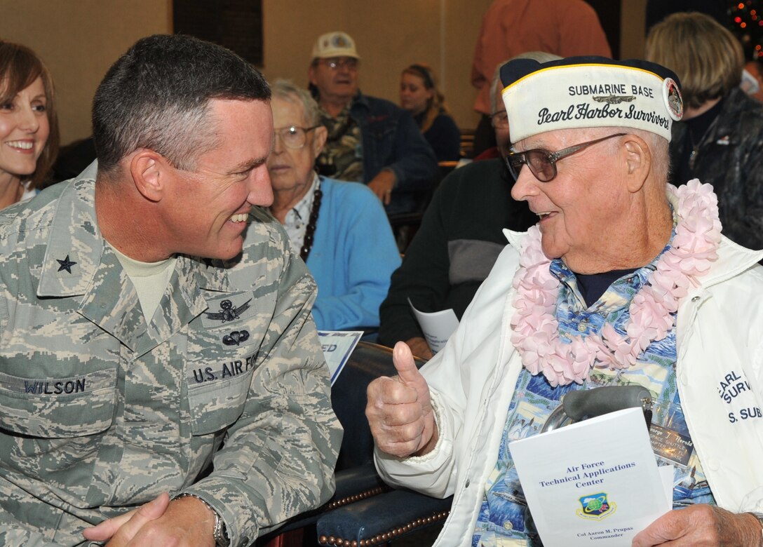 Mr. George J. Herold, one of the nine survivors present at the Patrick Air Force Base Pearl Harbor Memorial Ceremony hosted by the Air Force Technical Applications Center, is able to laugh with Brig. Gen. Ed Wilson, 45th Space Wing Commander, prior to the start of the ceremony on Dec. 7.  Also pictured (far left) is Gen. Wilson’s wife, Lisa.  69 years after the Japanese attacked the American fleet at Pearl Harbor on Dec. 7, 1941, the 9 men presnt at the Memorial Ceremony who survived the attack were honored here for their service as a tribute to the 2,388 men and women who were killed that fateful day “that will live in infamy”.  Another 1,178 people were wounded during the attack and 21 American warships were either sunk, beached, or damaged.  