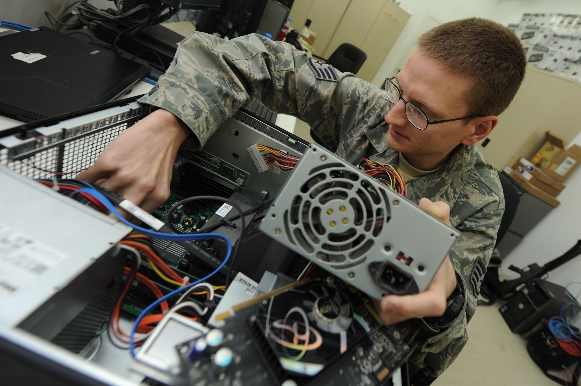 Staff Sgt. Spencer Penton installs a computer power supply unit Dec. 10, 2010, at Kandahar Airfield, Afghanistan. Airmen of the 451st Expeditionary Communications Squadron are responsible for managing, maintaining, and operating more than $30 million worth of equipment and keeping 2,000-3,000 customers happy. Sergeant Penton, from Eugene, Ore., is the NCO in charge of the client support team assigned to the 451st ECS. (U.S. Air Force photo by Tech. Sgt. Chad Chisholm/Released)