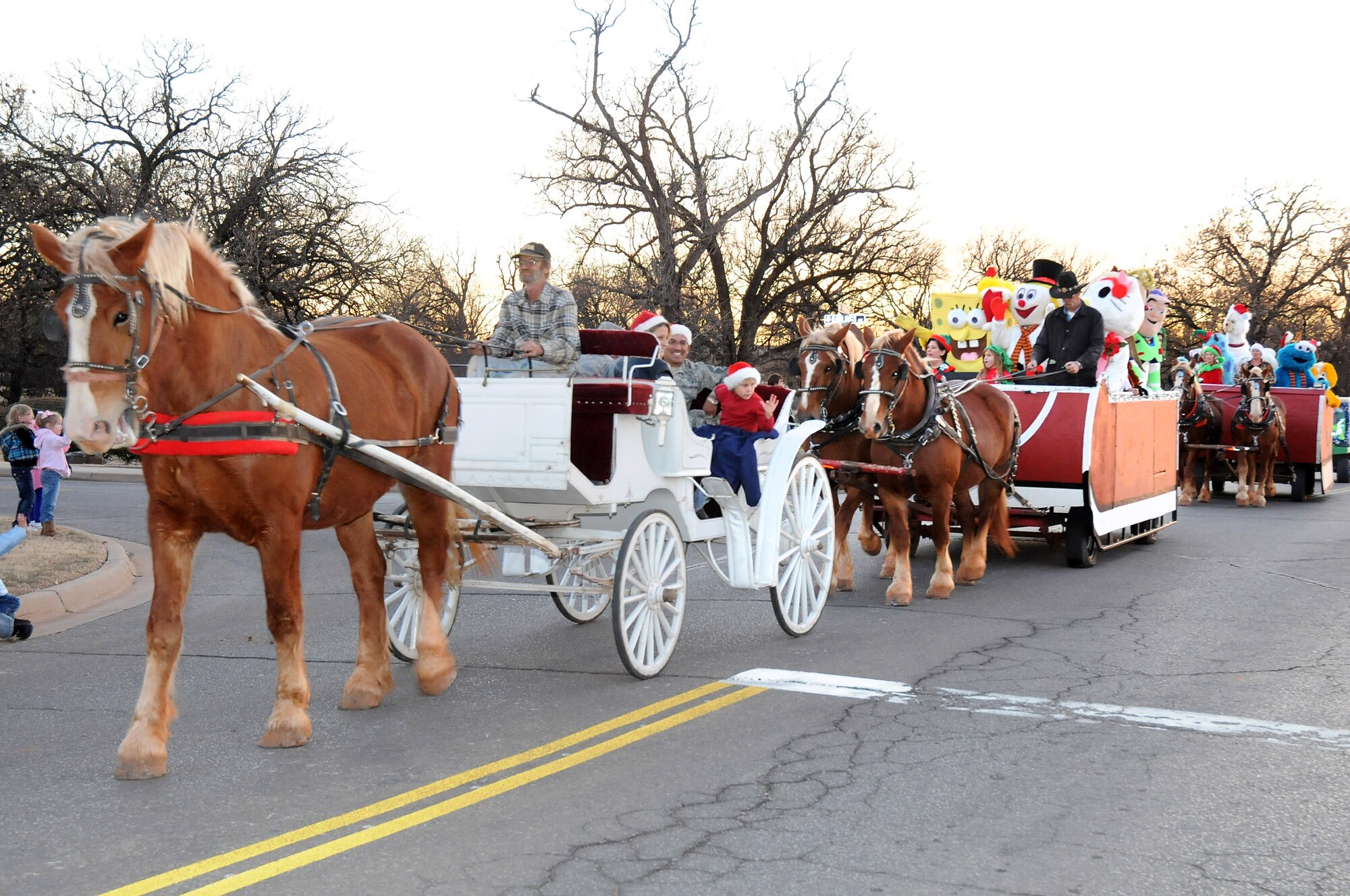 Warmer December weather brought Tinker families outside to line base housing streets for the annual Tinker Holiday Parade as it made its way to the Tinker Club. The parade was filled with horse-drawn sleighs carrying waving base leadership, Tinker emergency services vehicles, floats with costumed characters and volunteers tossing candy to children along the parade route. (Air Force photo by David Faytinger)
