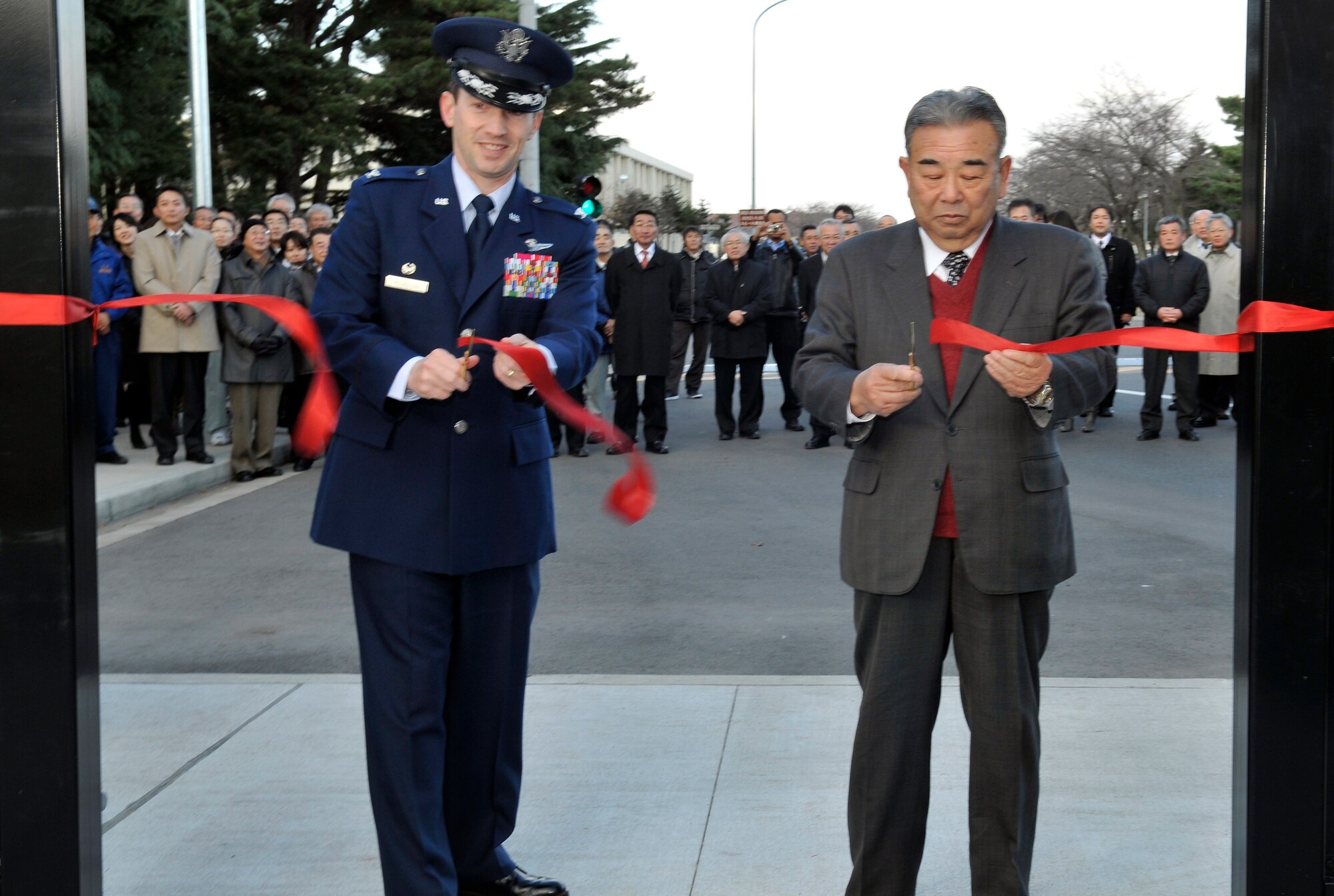 Col. Michael Rothstein, 35th Fighter Wing commander and Kazumasa Taneichi Misawa City Mayor, cut a ceremonial ribbon during the opening ceremony of the Misawa Air Base walking path Dec. 10, 2010. As a result of coordination between the city of Misawa and the 35 FW, the 35th Civil Engineer Squadron completed a walkway that runs alongside the base perimeter. The project was designed to revitalize the main gate area by reorganizing and integrating the present street layout and provide safe and comfortable environment in the main gate area. (U.S. Air Force photo by Tech. Sgt. Phillip Butterfield/Released)