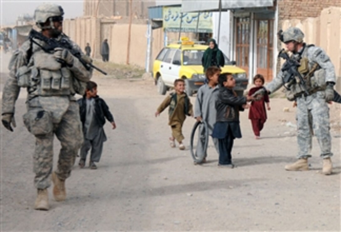 U.S. Army Staff Sgt. Kenneth Bower (right) and Spc. Robert Quinn, with Charlie Company, 1st Special Troops Battalion, 1st Brigade Combat Team, 4th Infantry Division, interact with children during a dismounted patrol through Popal colony in Kandahar City, Kandahar province, Afghanistan, on Dec. 5, 2010.  
