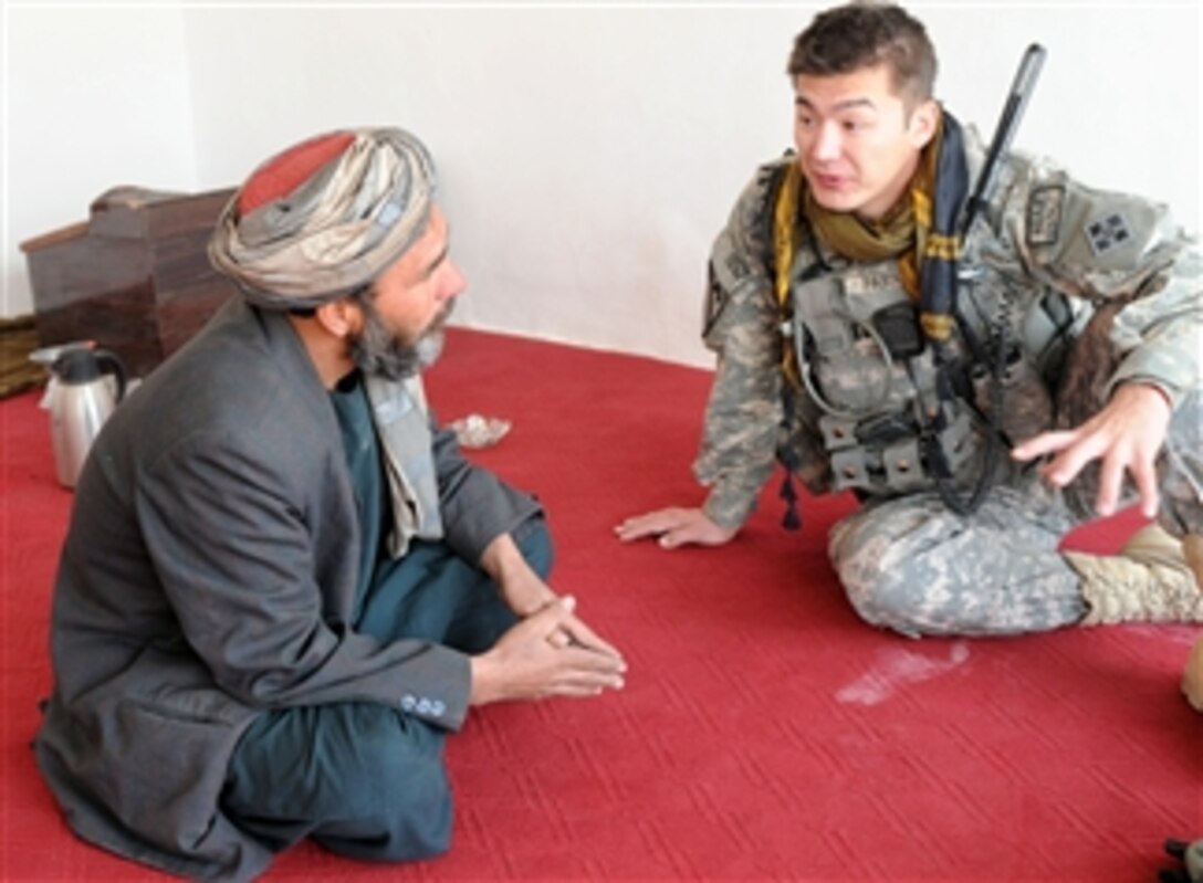 U.S. Army Capt. Michael Parks with Charlie Company, 1st Special Troops Battalion, 1st Brigade Combat Team, 4th Infantry Division discusses the progress of a canal cleanup with an elder in Kandahar City's Popal colony, Kandahar province, Afghanistan, on Dec. 5, 2010.  