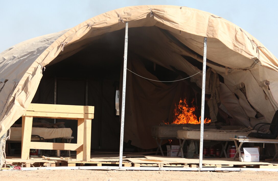 A fire spreads across a mattress to a tent wall during a fire simulation training exercise aboard Forward Operating Base Dwyer, Afghanistan, Dec. 10.  The Aircraft Rescue and Firefighting Marines with Marine Wing Support Squadron 373, 3rd Marine Aircraft Wing (Forward), completed the training to demonstrate how quickly a fire can start and spread throughout a tent.  Things to avoid are daisy chains, which are multiple circuits plugged into each other to extend another circuit, smoking and candles.  Tent inhabitants should also ensure their smoke detectors and fire extinguishers are working and should unplug any electronics not in use.